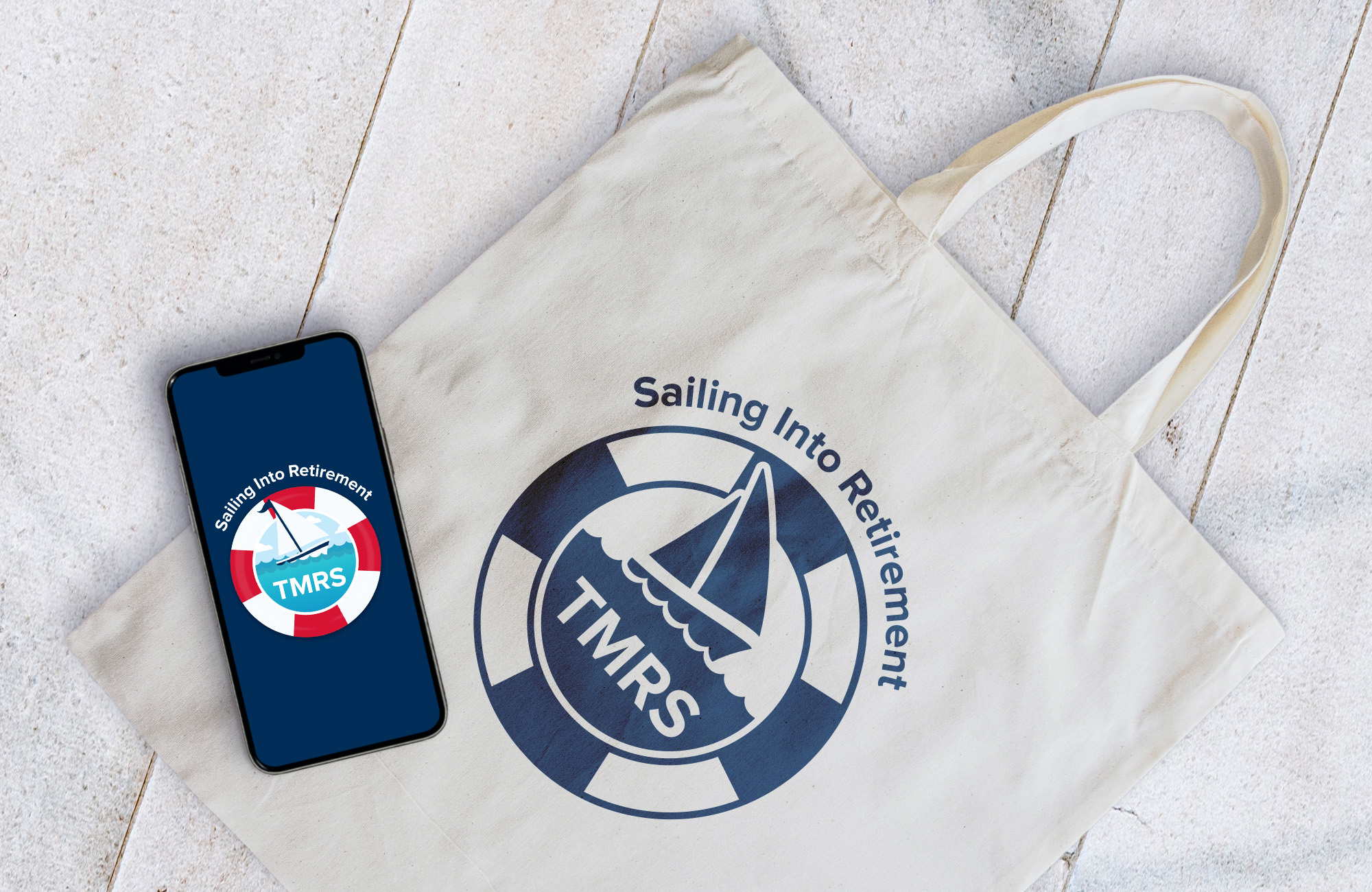 A phone open to a navy splash screen with a graphic resembling a sailboat encircled by a life preserver. Underneath the phone is a canvas bag with the same graphic.